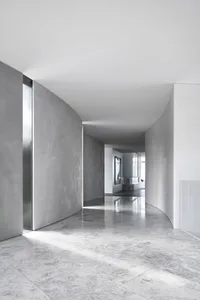 Modern minimalist living room with marble flooring and walls, featuring sleek, clean lines and a serene atmosphere.