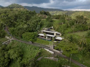 A modern residential house with concrete exterior and a pool on the hillside.
