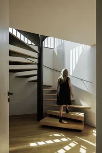 A woman walking up an industrial-style staircase with wood steps and a black metal railing.
