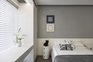 A minimalist bedroom with a grey and taupe color scheme, featuring a bed with white sheets and black and white pillows, a whi