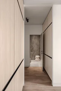Modern minimalist interior featuring light-colored wooden walls and a stone floor, with a white sculptural object in the bath