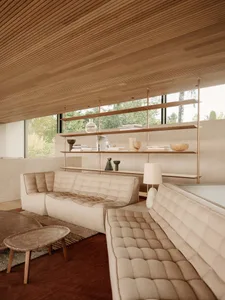 A modern minimalist living room with neutral-toned furniture and wooden shelves.