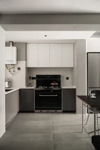 Modern kitchen with concrete flooring, minimalist design, white and black cabinets, and a black stove.