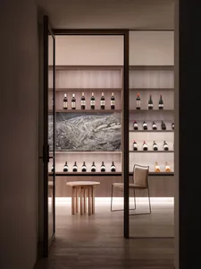 A minimalist wine storage room featuring wooden shelves, glass bottles, and a marble backsplash.