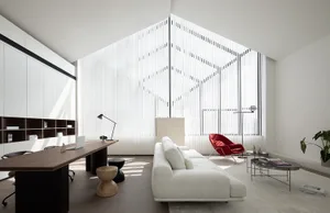 A modern minimalist living room with a white sofa, red chair, and large windows.