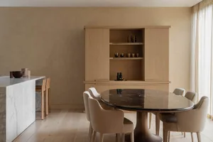 A modern residential interior with a marble dining table and wood cabinet.