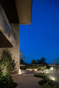 A nighttime view of a minimalist hotel terrace featuring mixed materials and sleek design elements.