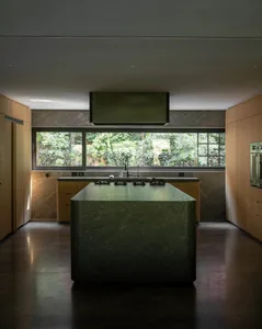 Modern kitchen with a marble island and large windows overlooking greenery.