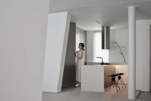 Modern, minimalist kitchen with white concrete surfaces, stainless steel appliances, and a sleek design.