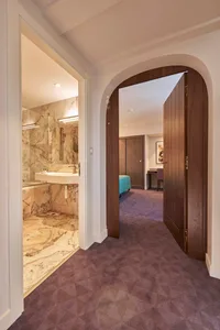 View of a luxurious marble bedroom suite, featuring elegant wooden doors and a contemporary design.
