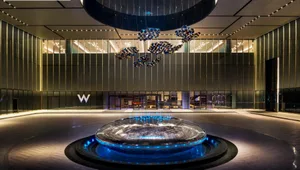 A modern hotel entry with marble floors, metal sculptures, and glass walls.