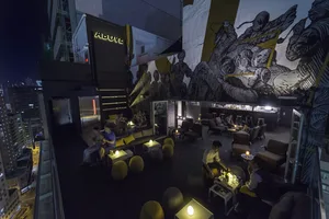 A rooftop bar with modern seating and a mural of warriors.