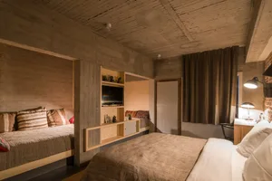 Modern bedroom featuring exposed concrete walls and a large bed with a minimalist design.