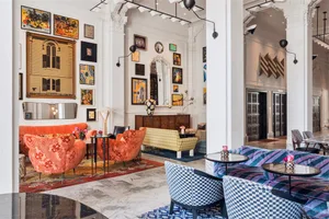 A vibrant, modern hotel lobby featuring concrete walls, patterned furniture, and a variety of art installations.