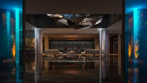 A modern lobby with glass partitions and a geometric ceiling decoration.
