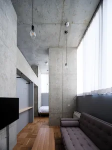 A minimalist living room with concrete walls and a large window.