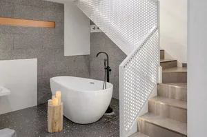 Modern industrial bathroom with a glass floor, freestanding bathtub, and minimalist styling.