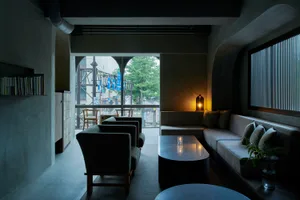 A minimalist industrial living room with concrete walls, large windows, and a modern sofa.