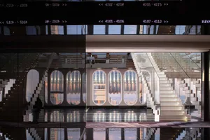 Staircase made of glass with concrete steps leading up to a glass wall