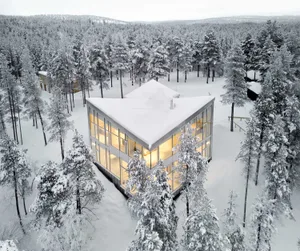 一座現代住宅建築，周圍環繞著覆雪的樹木。