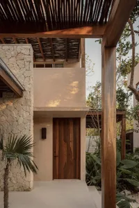 A modern house exterior with a wooden door and stone walls.