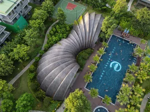 Aerial view of an architecturally designed swimming pool surrounded by greenery and trees.