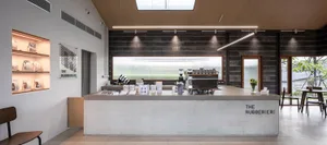 A modern coffee shop interior with a counter displaying cups, bottles, bowls, and books, creating a cozy atmosphere for conversation and reading