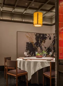 Elegant dining space with a wooden table and chairs, surrounded by potted plants and fine dining decor