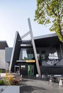 A modern building with a green door and glass facade, featuring a bright and airy interior with natural light and several chairs