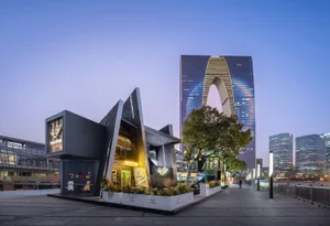 A modern building with a triangular shape and an archway, situated in a city environment with a blend of functionality and artistic expression