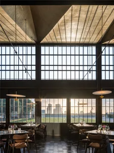 A restaurant interior with multiple dining tables, large windows, and wine glasses, creating a bright and inviting atmosphere