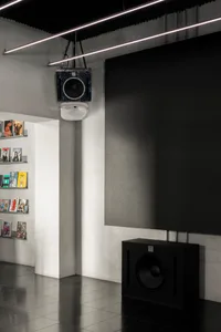 Cozy study with a large black speaker, multiple books, and a mounted TV in a modern and minimalist interior