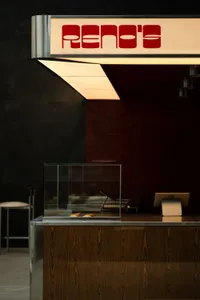 Inviting restaurant interior with a counter, glass display case, and two chairs, showcasing food options