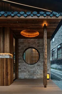Small Asian-style room with a stone wall, round window, and two side lights, creating a calm and serene atmosphere