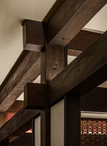 Rustic living and dining space with a wooden beam supporting the ceiling, wooden furniture, and a warm ambiance