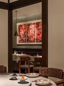 A cozy dining area with a wooden table, multiple chairs, wine glasses, and bowls, set in a warm and inviting atmosphere