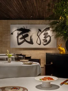 Cozy Asian restaurant interior with dining tables, chairs, artwork on the walls, and vases on the tables