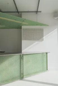 Modern kitchen with green walls, white countertops, and two sinks, featuring a metallic appearance possibly made of stainless steel