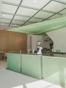 A modern kitchen with green walls, a countertop, chairs, a blender, cups, and bottles, creating a well-equipped and functional space