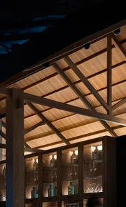 Cozy interior space with wooden beams and ceiling, featuring bottles and a warm atmosphere