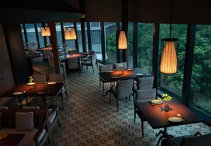 A modern restaurant interior with multiple tables, chairs, and vases, featuring a well-lit and sophisticated atmosphere