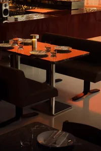 A warm and inviting dining area with an orange table surrounded by chairs, wine glasses, and a cozy atmosphere