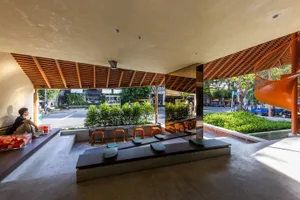 A wooden bench and chairs create a cozy seating area in a room with a natural atmosphere, surrounded by trees outside