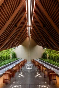 A long hallway with wooden benches and chairs, creating a calm and inviting atmosphere with warm wooden elements