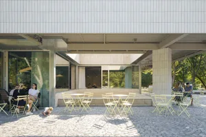 An outdoor cafe with several dining tables and chairs, umbrellas providing shade, and a comfortable atmosphere for socializing