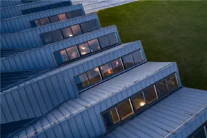 A modern urban building with blue roofs and windows, featuring metal cladding and a sophisticated design