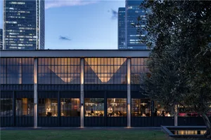 A modern restaurant with large glass windows, natural light, and interior seating for patrons