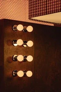 Bathroom with wooden walls, a mirrored cabinet, and three wall lights, giving off an elegant and sophisticated vibe