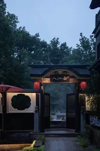 Traditional Asian entrance with a wooden structure and red roof, featuring two people standing near the doorway