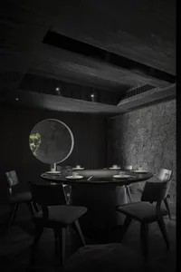 A round dining table surrounded by chairs in a restaurant, adorned with cups and bowls, creating a cozy atmosphere